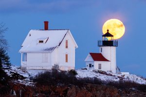 The full moon rises behind the Curtis Island Lighthouse