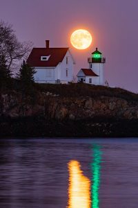 A full moon rising over Curtis Island Lighthouse.