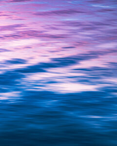 Pink and blue waters reflecting the sunset above.