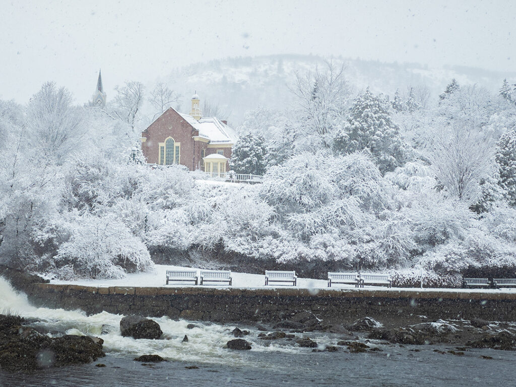 A snowy scene featuring the Camden Public Library surrounded by flocked trees with Mount Battie rising above in the background.