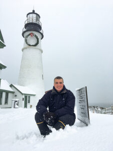 Bob Trapani, Jr. sits beneath the Portland Head Lighthouse after a snowfall.